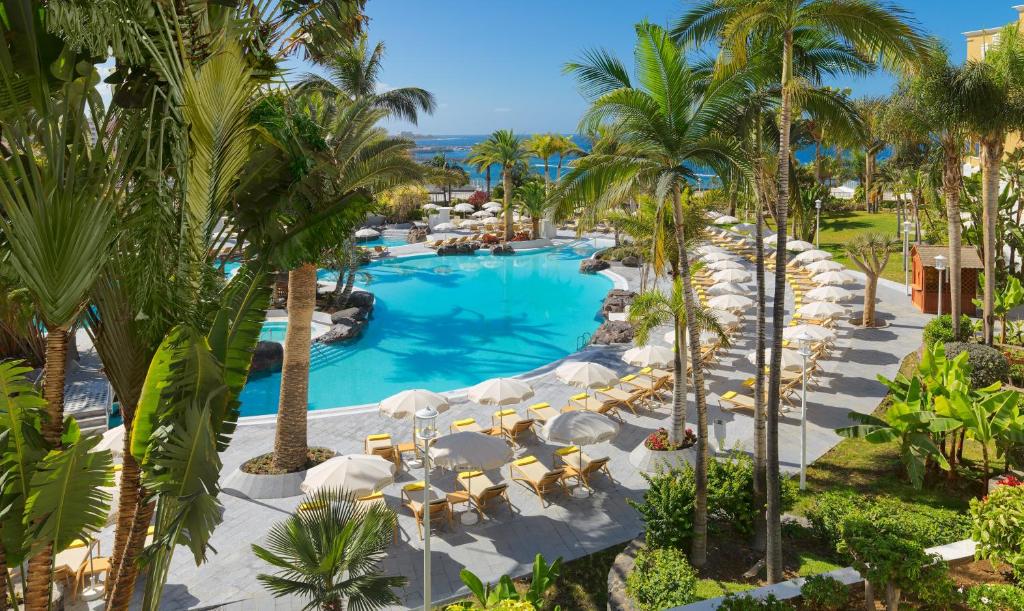 einen Luftblick auf einen Pool mit Palmen des Resorts in der Unterkunft Adrián Hoteles Jardines de Nivaria in Adeje