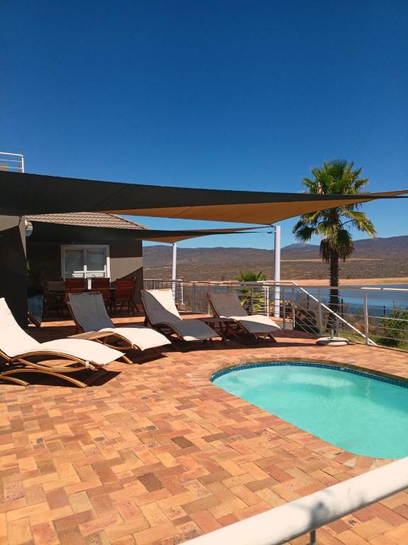 a swimming pool with lounge chairs and a table at Clanwilliam Waterside Villa in Clanwilliam