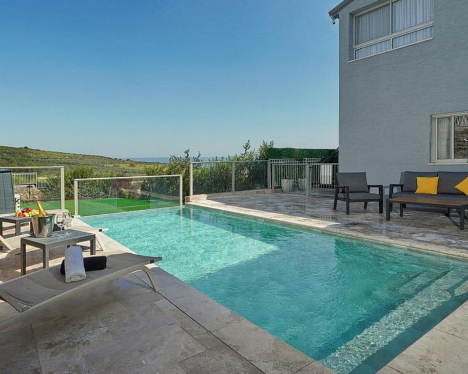 a swimming pool with chairs and a house at וילה ג'נסיס - וילה מהממת למשפחות עם בריכה פרטית מחוממת ליד הכנרת in Migdal