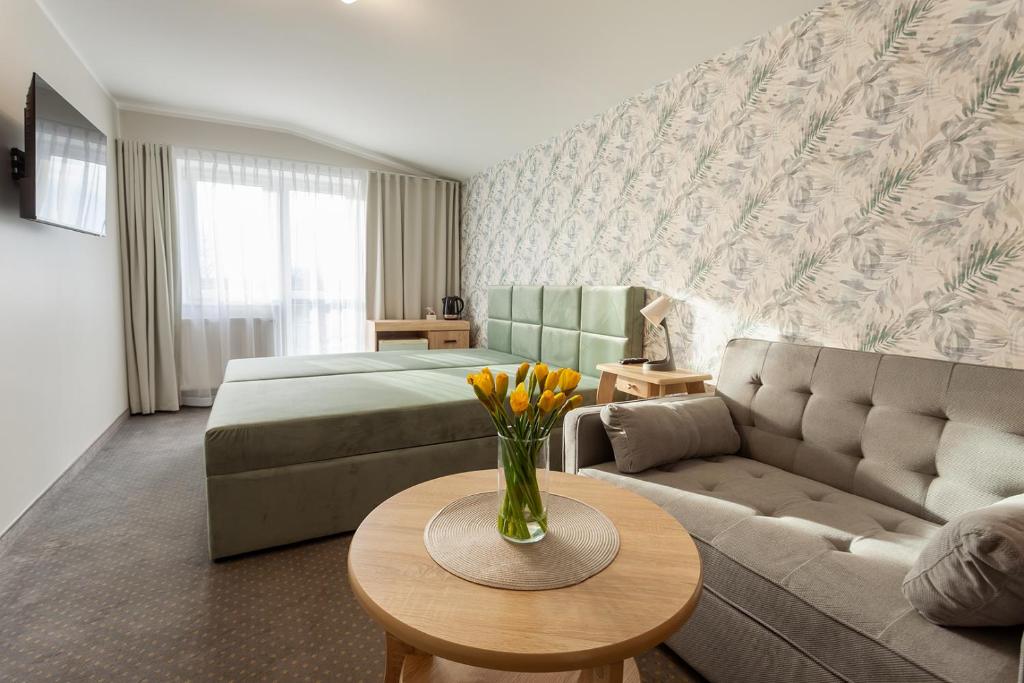 a hotel room with a bed and a couch at POKOJE APARTAMENTY ANASTAZJA in Grzybowo