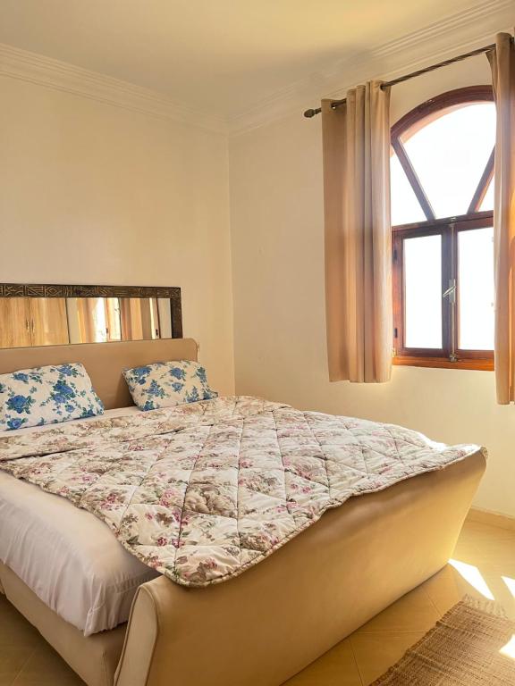 a bedroom with a bed with a comforter and a window at Tamraght Sunny apartment in Tamraght Ouzdar