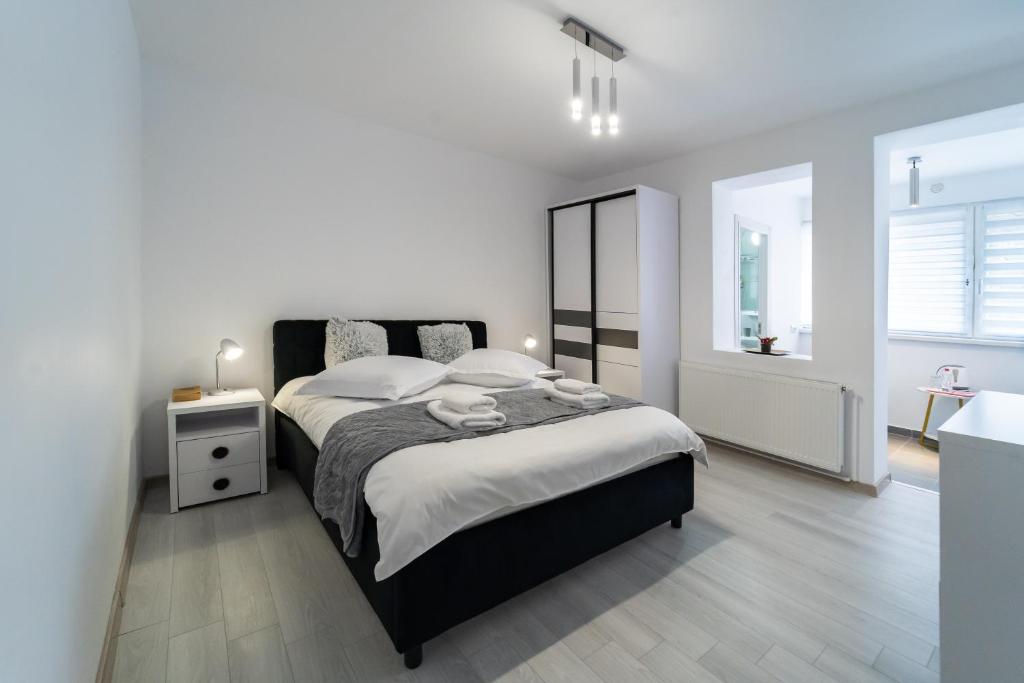 a white bedroom with a large bed and a window at Vila Petro in Iaşi