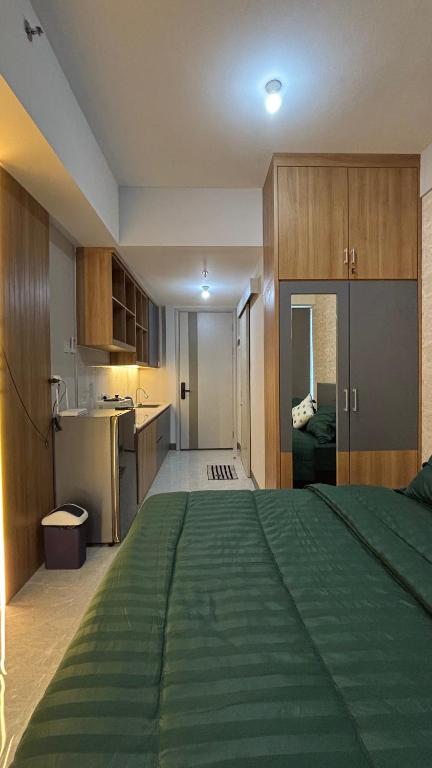 a large bedroom with a green bed and a kitchen at Sorici Studio at Bella Tower in Surabaya