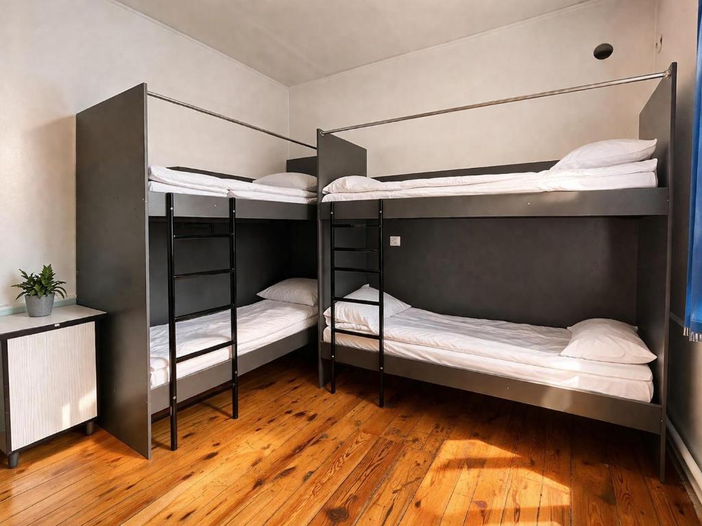three bunk beds in a room with a wooden floor at Sunny Hostel in Osh