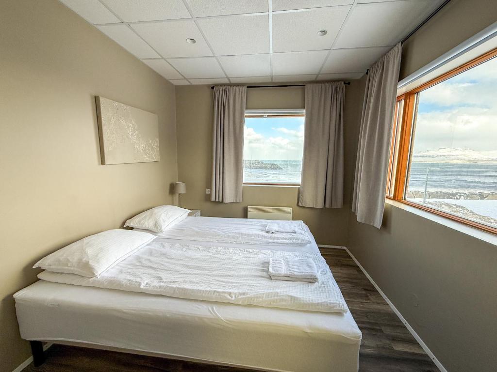 a bedroom with a bed and a large window at Við Hafið Oceanfront Guesthouse in Ólafsvík