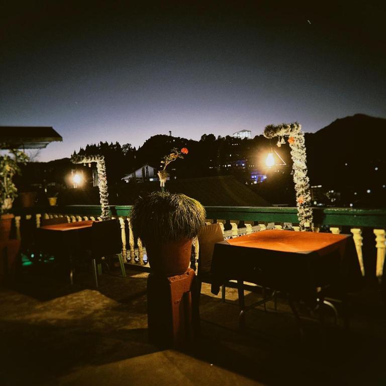 a patio at night with two tables and lights at Hotel Kabur in Pelling