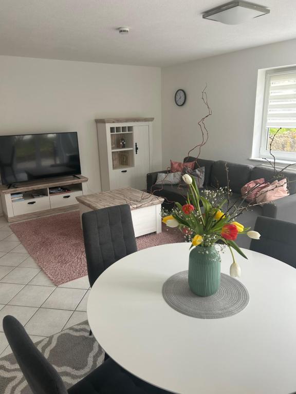 a living room with a white table with flowers on it at Ferienwohnung Schwarzwaldrand in Nagold