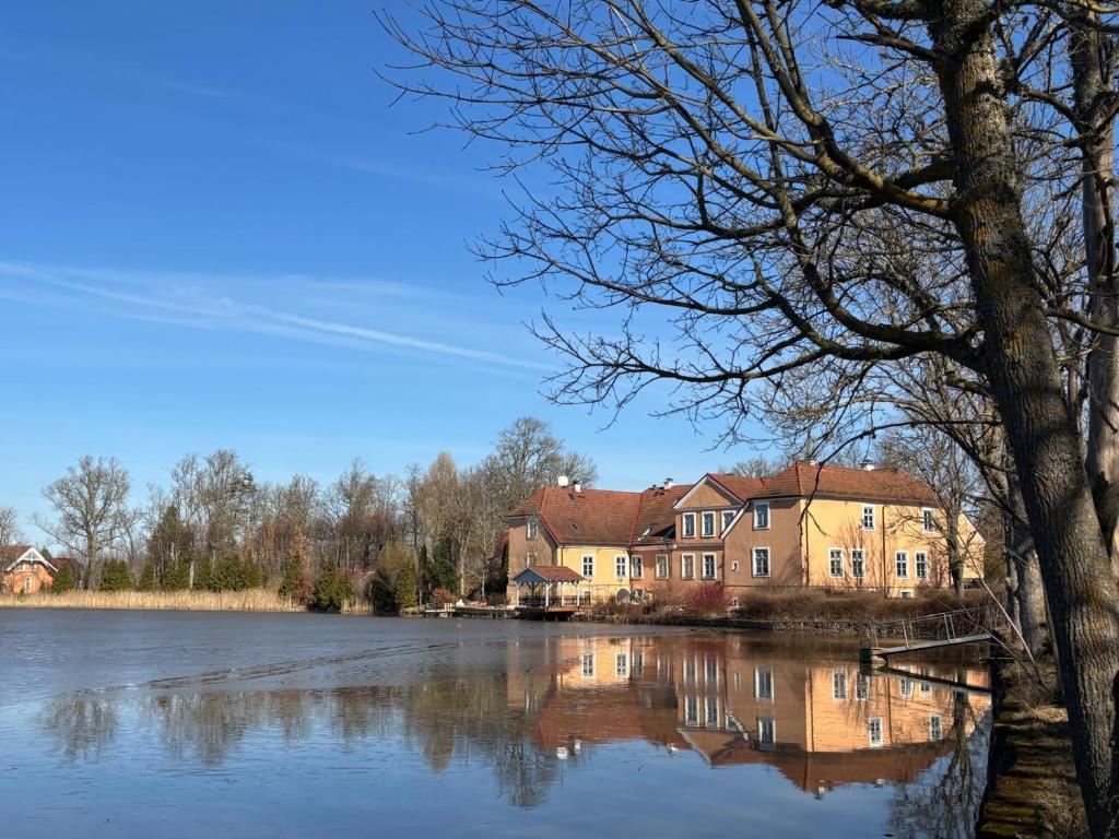 a house sitting next to a large body of water at Kukšu muiža in Kukšas