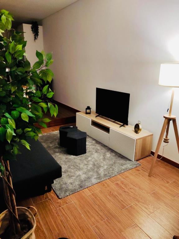 a living room with a flat screen tv on a white cabinet at Ribeira Mar Guesthouse in Viana do Castelo
