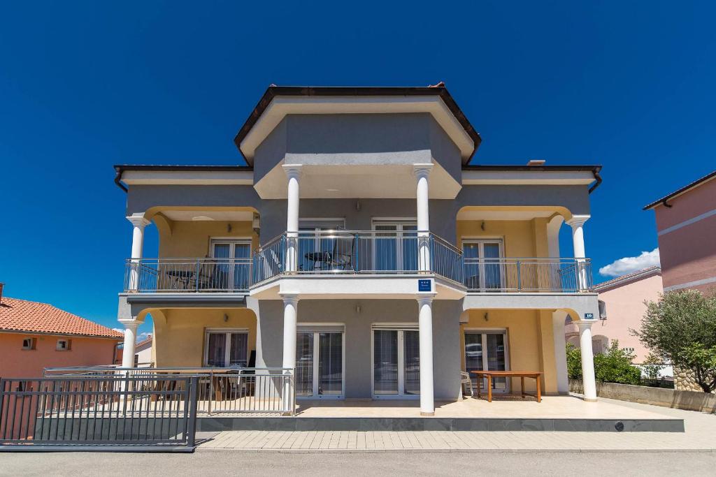 a large yellow house with a balcony on a street at Apartment Dea 3 Spacious Lower-Level Apartment in Crikvenica