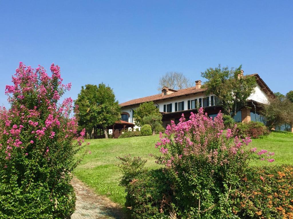 une maison avec des fleurs roses devant une cour dans l'établissement Locanda Dell'Arzente, à San Salvatore Monferrato