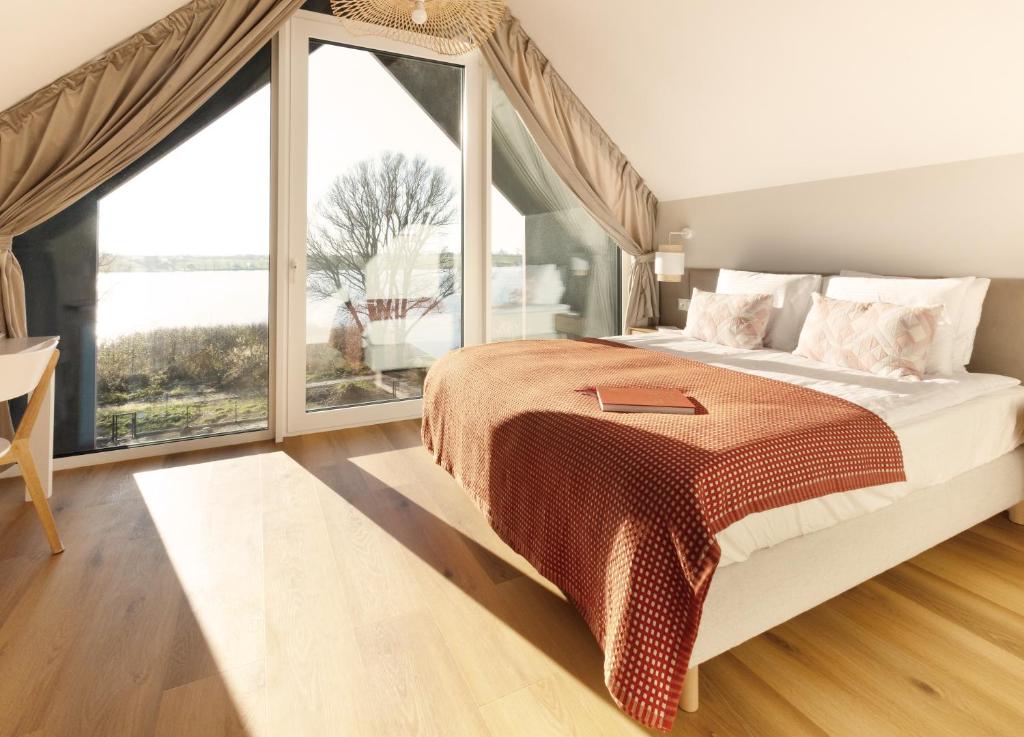 a bedroom with a large bed and a large window at Sen Topoli - Domy nad jeziorem I Sauna I Plaża I 30 min od Torunia in Mirakowo