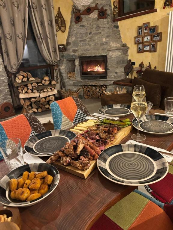 a table with plates of food and a fireplace at La Baita del vecchio GAD in Oulx