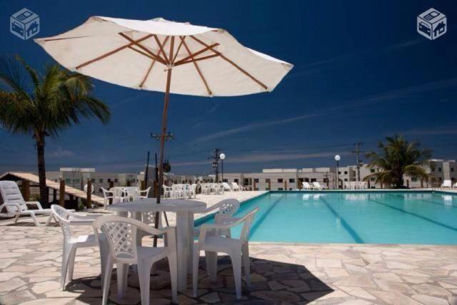 una mesa, sillas y una sombrilla junto a la piscina en Apto Cabo Frio Marina Clube, en Cabo Frío