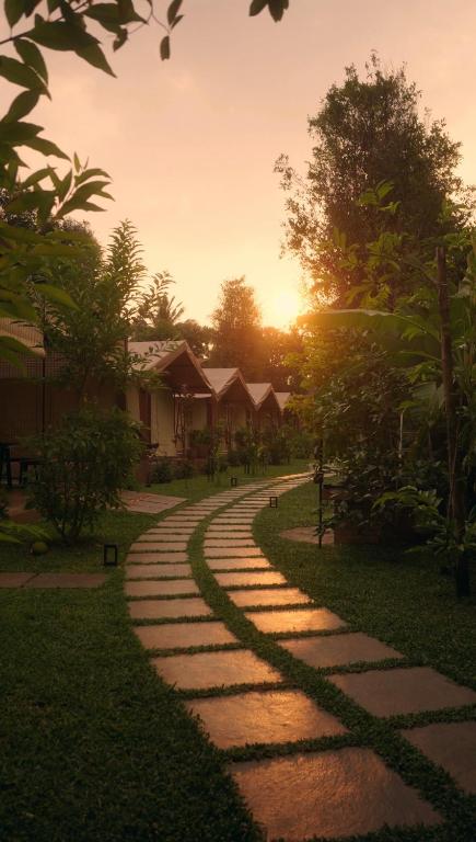 a stone path leading to a house with the sunset in the background at Vanantara Riverside Eco Retreat in Cochin