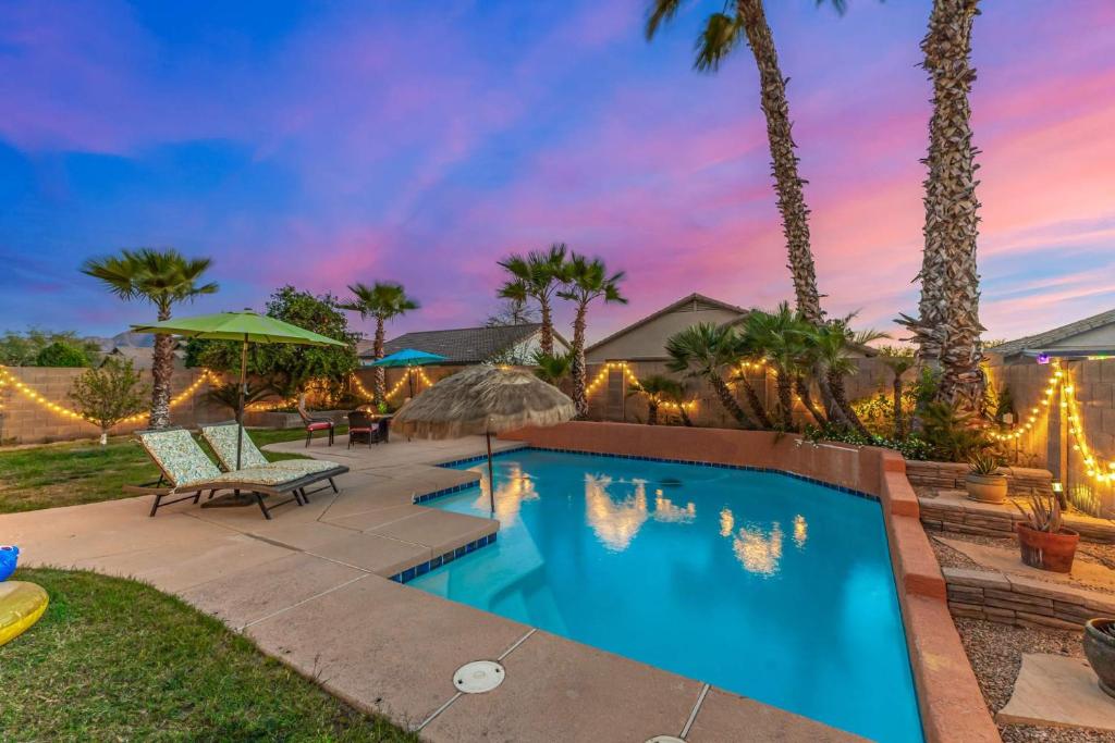 a swimming pool in a backyard with palm trees at Pet-Friendly 4BR Oasis - Heated Pool Firepit & BBQ in Chandler