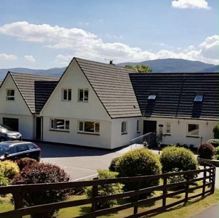 a house with a car parked in a parking lot at Lochview Guest House in Ullapool