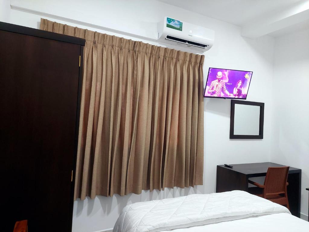 a bedroom with a bed and a tv on the wall at Skyline Residence in Wadduwa