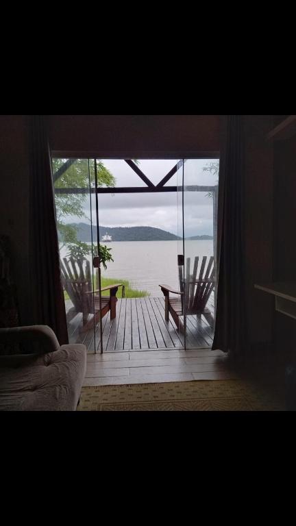 a room with a sliding glass door with a view of the water at Piaça House - Piaçaguera -Pr in Paranaguá