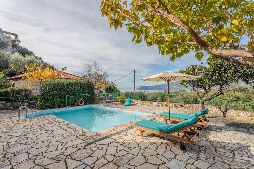 ein Swimmingpool mit Sonnenschirm, zwei Liegestühlen und einem Sonnenschirm in der Unterkunft Palataki in Kardhamili