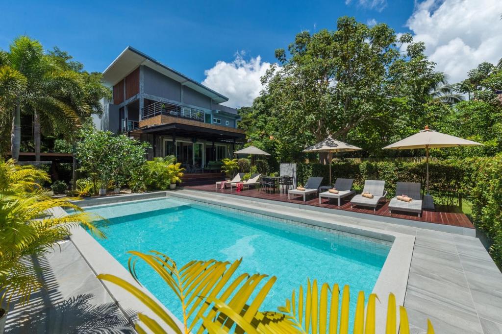 a pool with chairs and umbrellas in front of a house at Siya Private Pool Villa Ao Nang in Ao Nang Beach