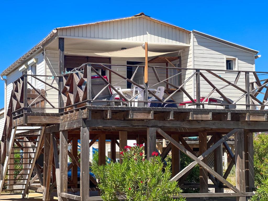 a house on a wooden structure with a deck at L'authentique chalet en bois sur pilotis in Gruissan