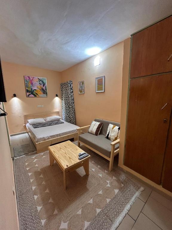 a living room with a bed and a couch at Studio meublé Aéroport cité SIPIM in Abidjan