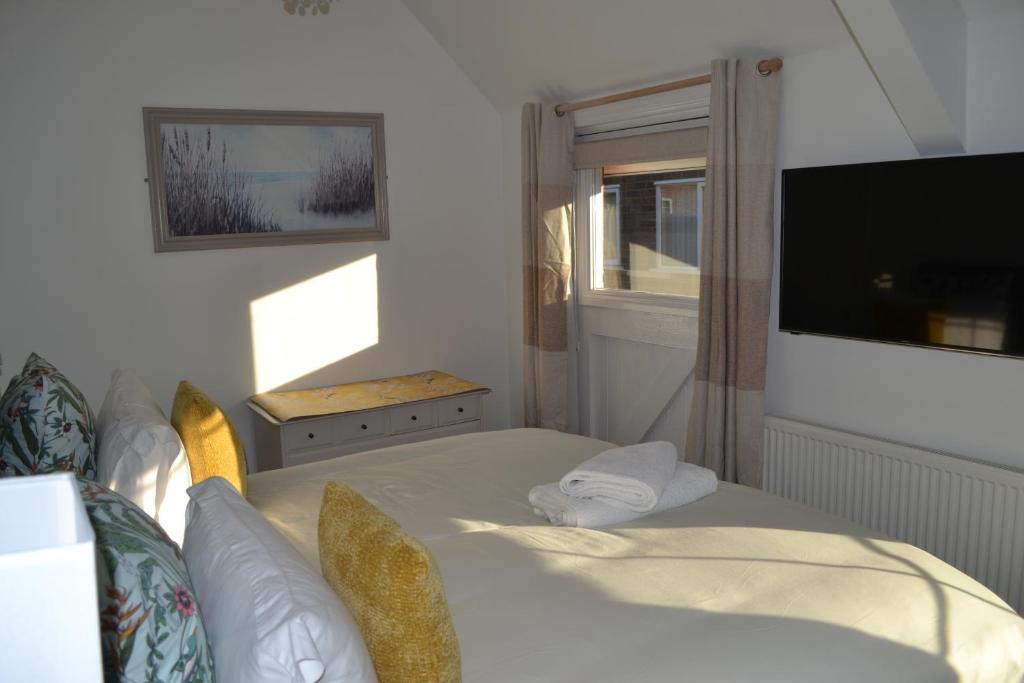 a bedroom with a bed and a tv and a window at Frinton Escapes - The Cottage in Frinton-on-Sea