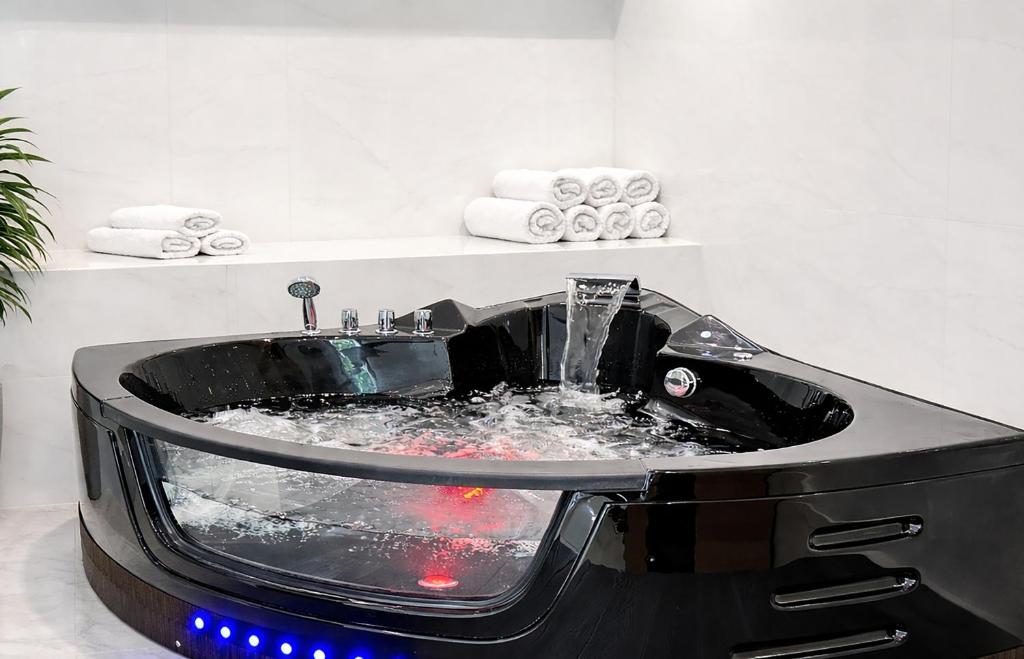 a black bathtub with water in it in a bathroom at Romantica SPA Kraków in Krakow