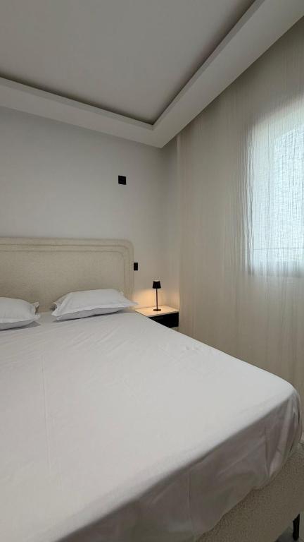 a white bed in a room with a window at La perle in Sukrah