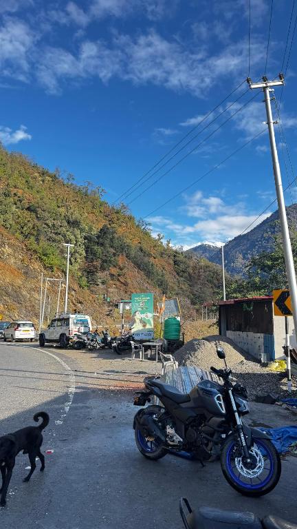 a black dog walking next to a motorcycle on the street at Hotel Himalayan View Kedarnath in Phata