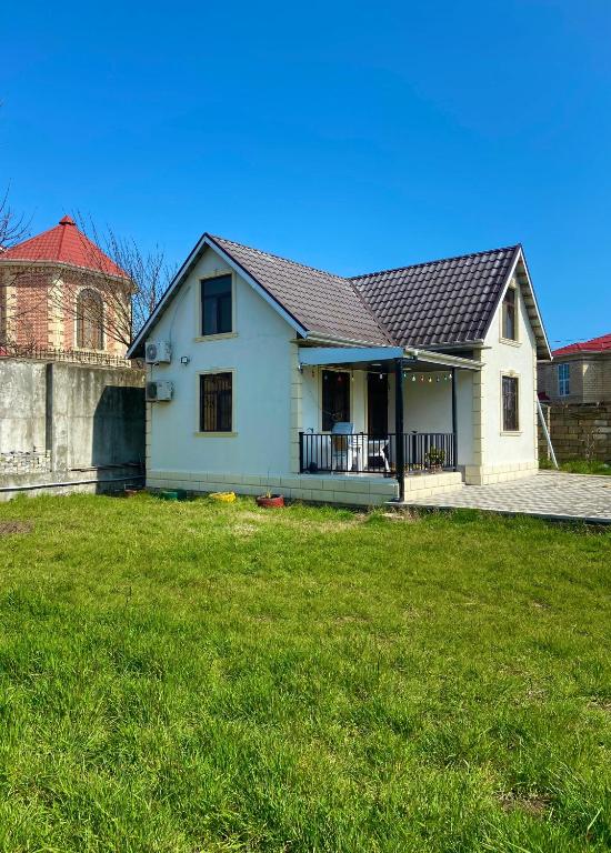 a white house with a red roof and a yard at Praqa House in Lankaran