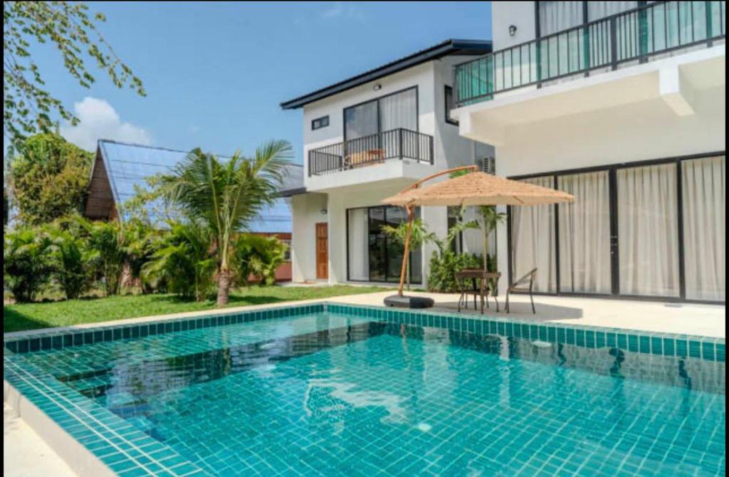 a swimming pool in front of a house at Sharing Pool Villa Sritanu in Ko Phangan