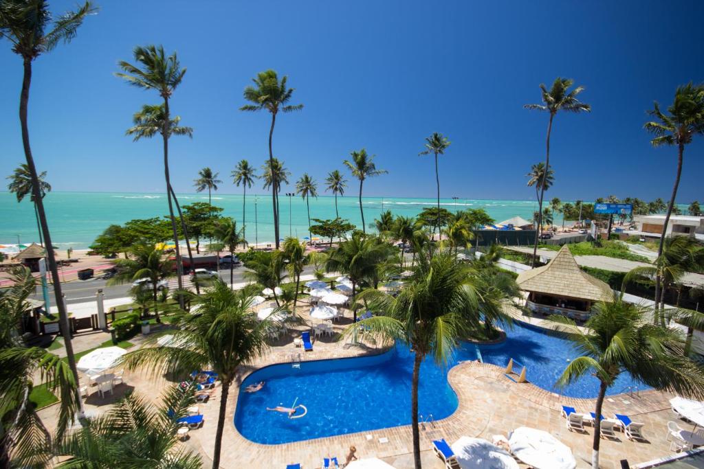 an aerial view of a resort with a pool and the ocean at Maceió Atlantic Suites in Maceió