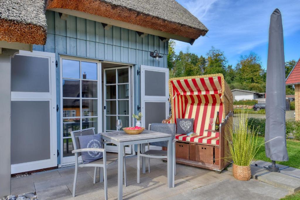 a patio with a table and chairs and a house at Ferienhaus Boddenlust 24 Feriendorf Klein Stresow Rügen by ruyastay in Putbus