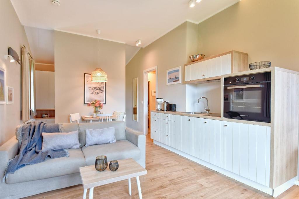 a living room with a couch and a kitchen at Ferienhaus Lotta Feriendorf 29 Klein Stresow Rügen by ruyastay in Putbus