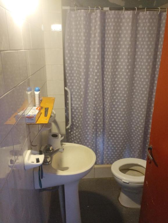a bathroom with a toilet and a sink and a shower curtain at Refugio Pampa - General Pico in General Pico