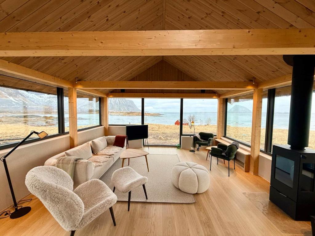 a living room with a couch and chairs and the ocean at Storøya Lodge Lofoten in Vestvågøya