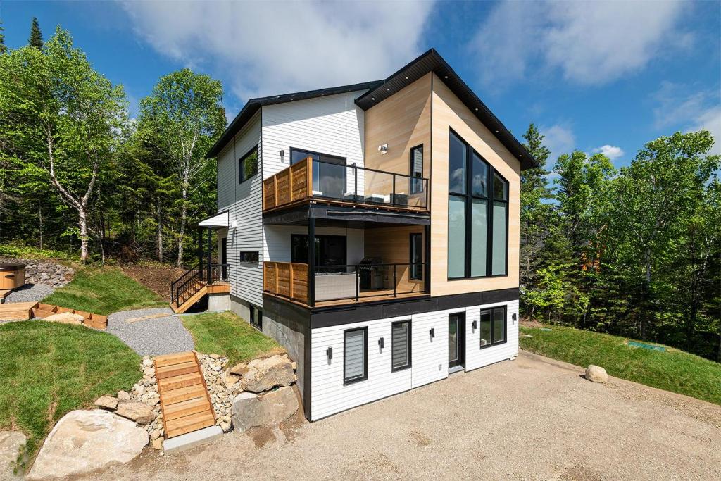 a large white house with a balcony on a hill at Käbane Horizon Boréal - Le Belvédère in Les Éboulements