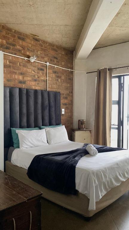 a bedroom with a large bed with a brick wall at 201 On Main in Johannesburg