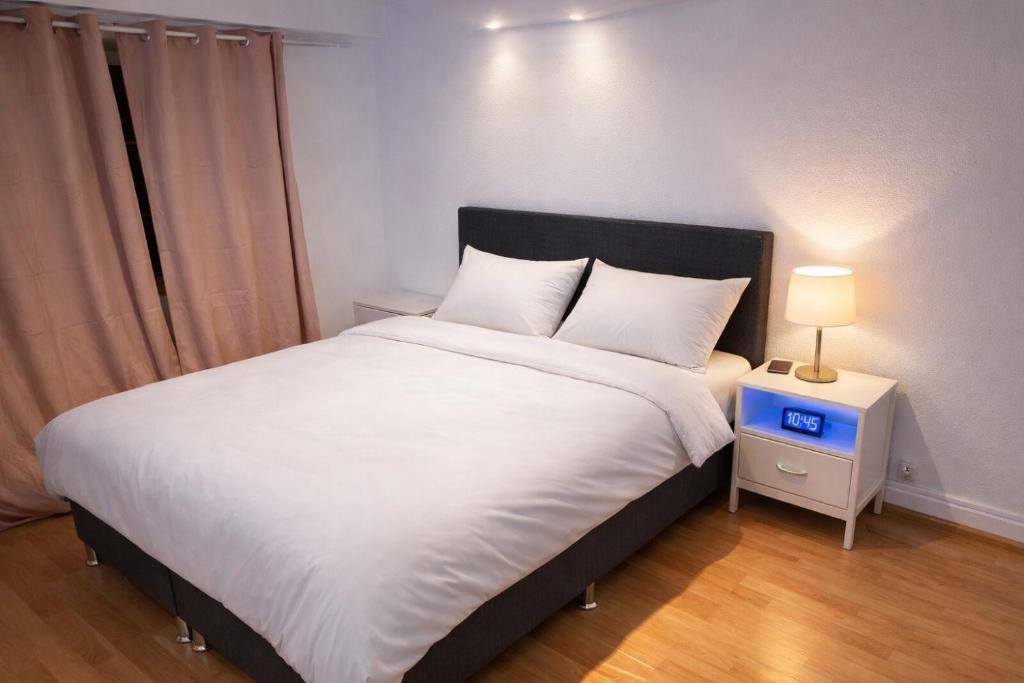 a bedroom with a large white bed with a night stand at Rooms4Rent in Bottmingen