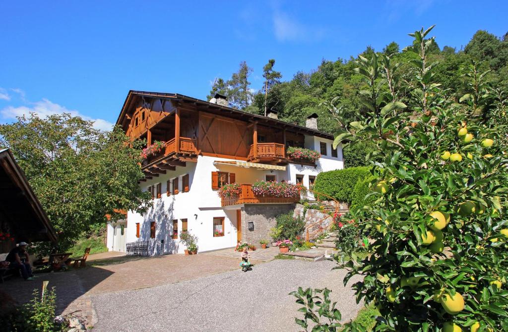 a large white building with a balcony and trees at Prackfiedererhof in Funes