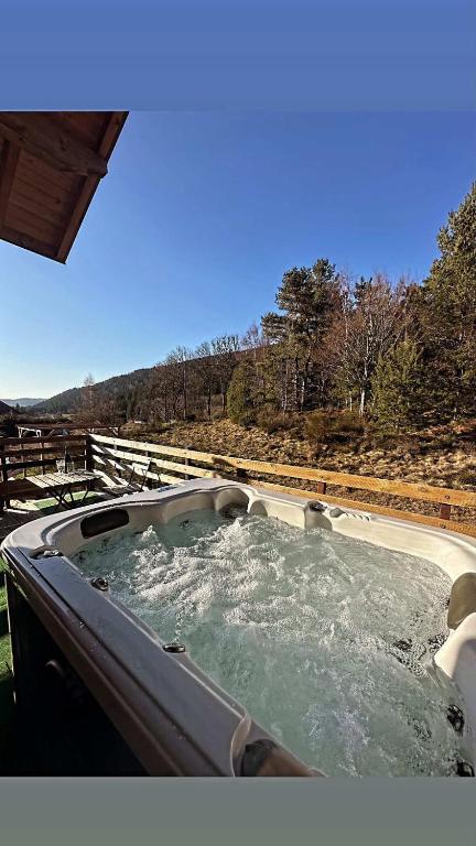 a hot tub with water in it next to a hill at Grange de l'ancienne école avec Jacuzzi privé in Gérardmer