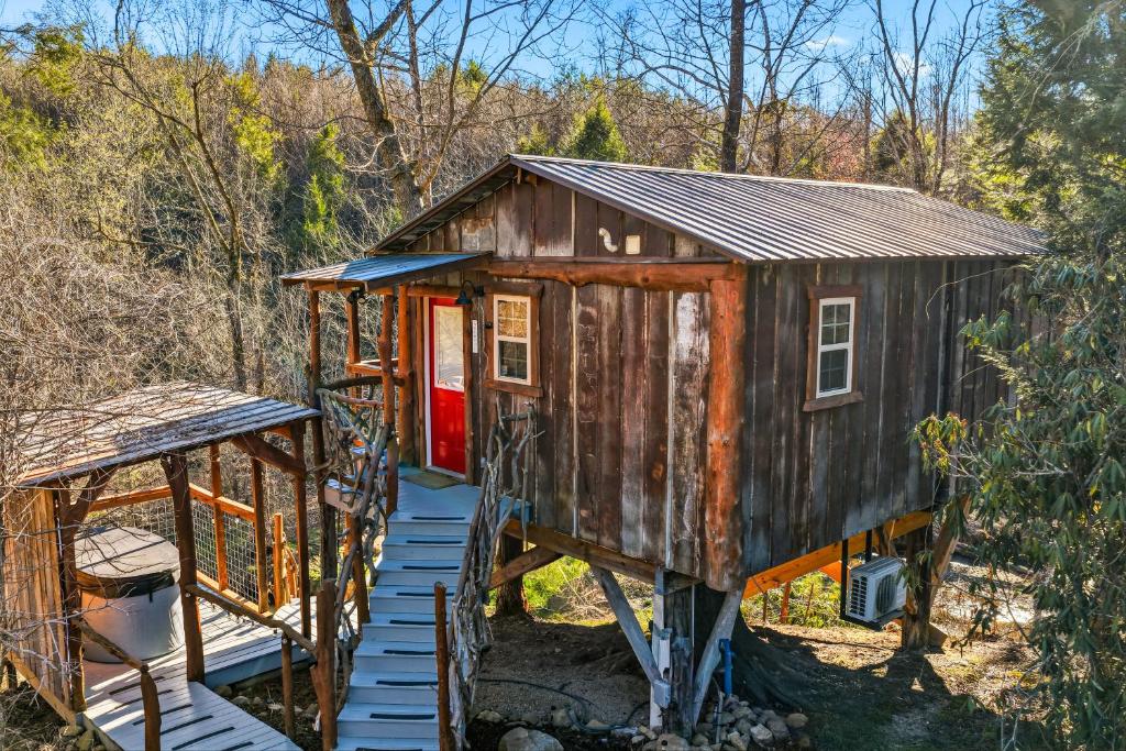 a tiny house with a red door and a porch at Creekside Treehouse in Cosby