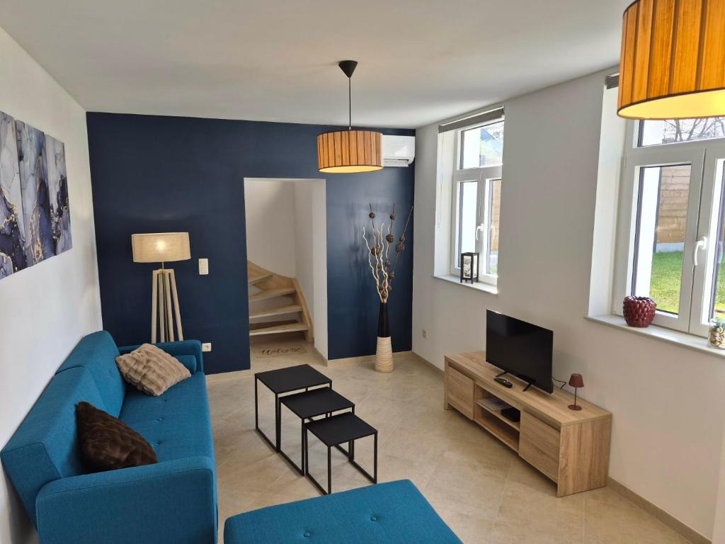 a living room with a blue couch and a tv at Le Fond du Village in Solre-Saint-Géry