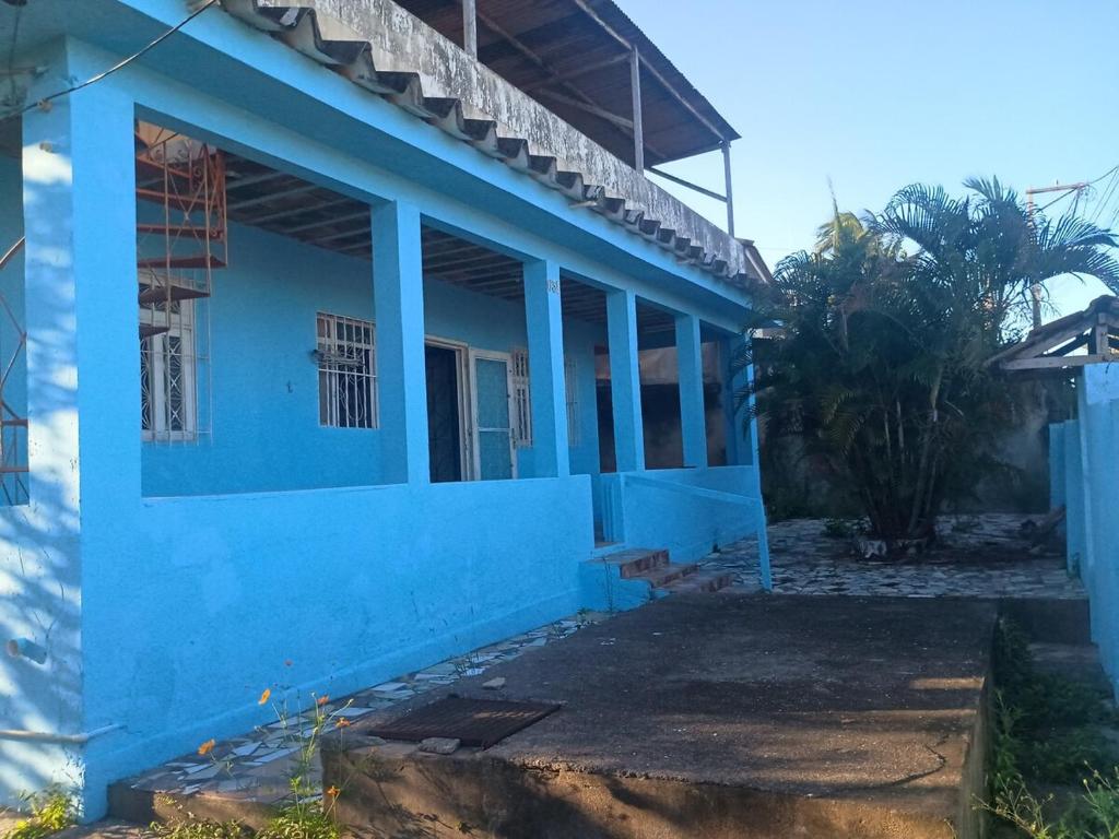 a blue house with a palm tree in front of it at Casa em Araruama com 3 quartos e muito arejada in Araruama