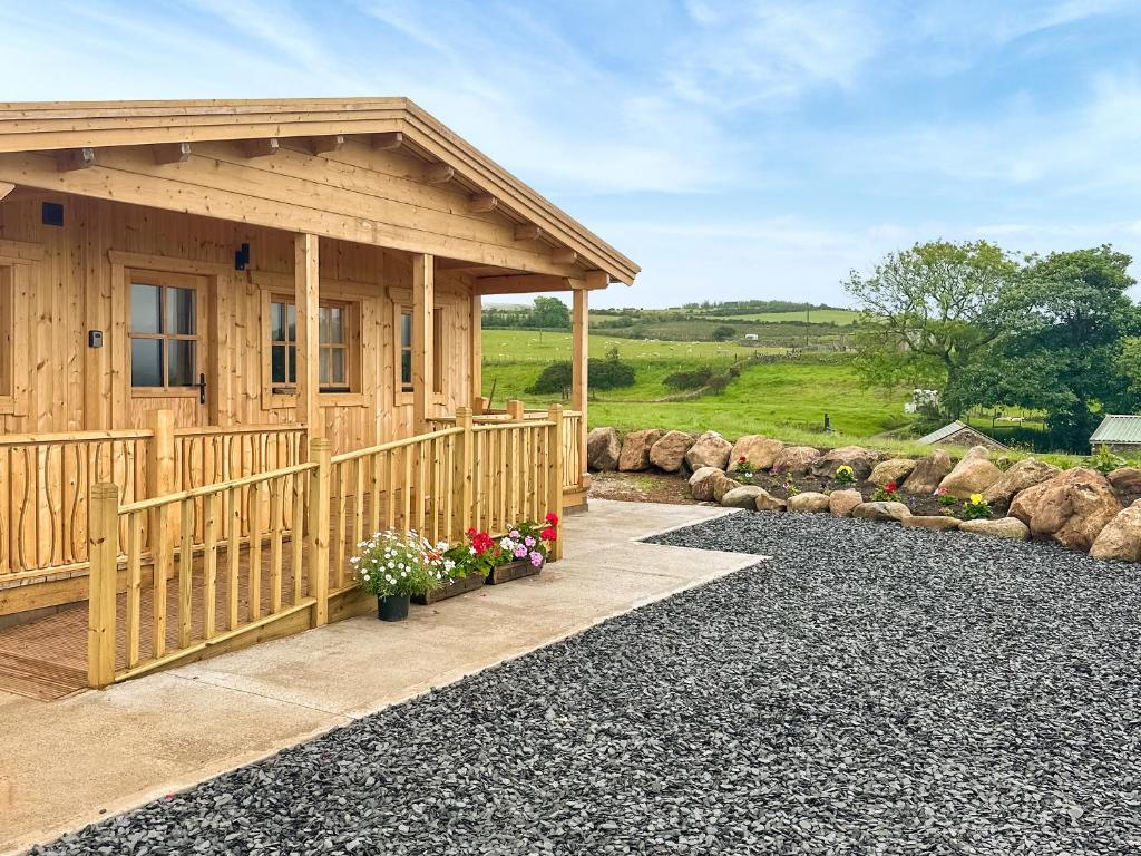 a wooden cabin with flowers in front of it at Wind Hall Log Cabin in Gosforth