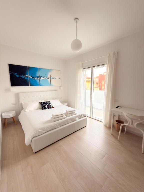 a white bedroom with a large bed and a window at Riganvì Affittacamere Sestu in Sestu