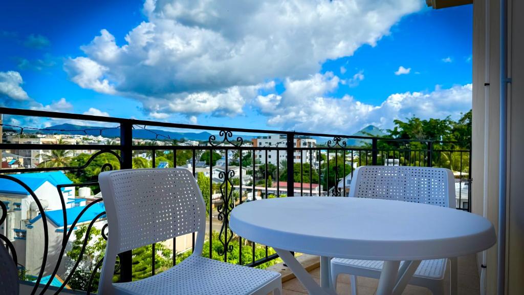a white table and chairs on a balcony with a view at Le Verger Sur Mer in Flic-en-Flac