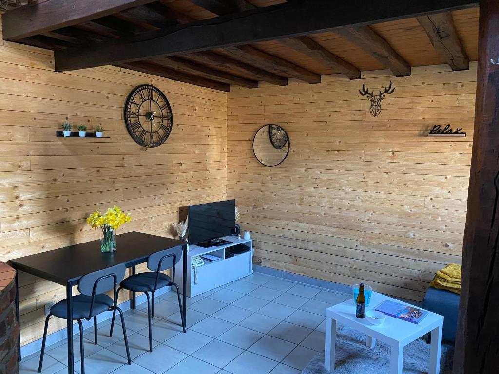 a room with a table and chairs and a clock on the wall at L Abri douillet in Libin